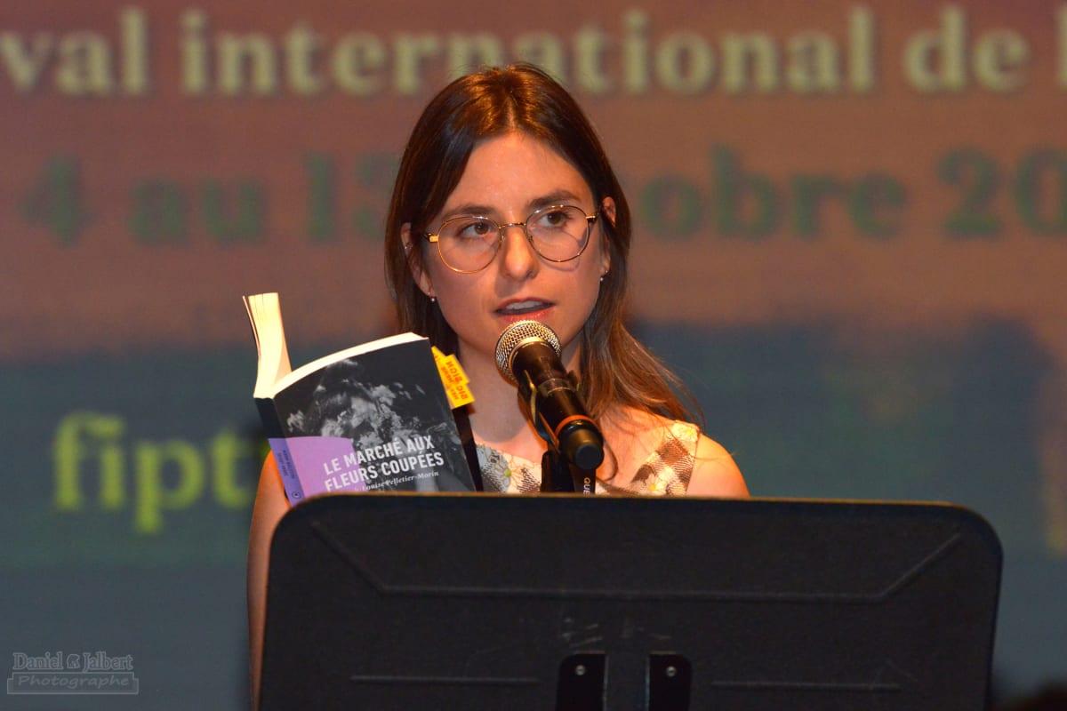 Young girl reading in front of an audiece at a conference at the international poetry Festival in Trois-Rivières.