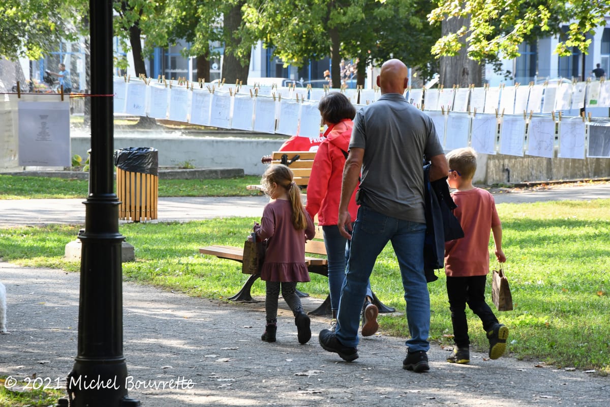 Family walking on a trail next to a rope of poems in Trois-Rivières.