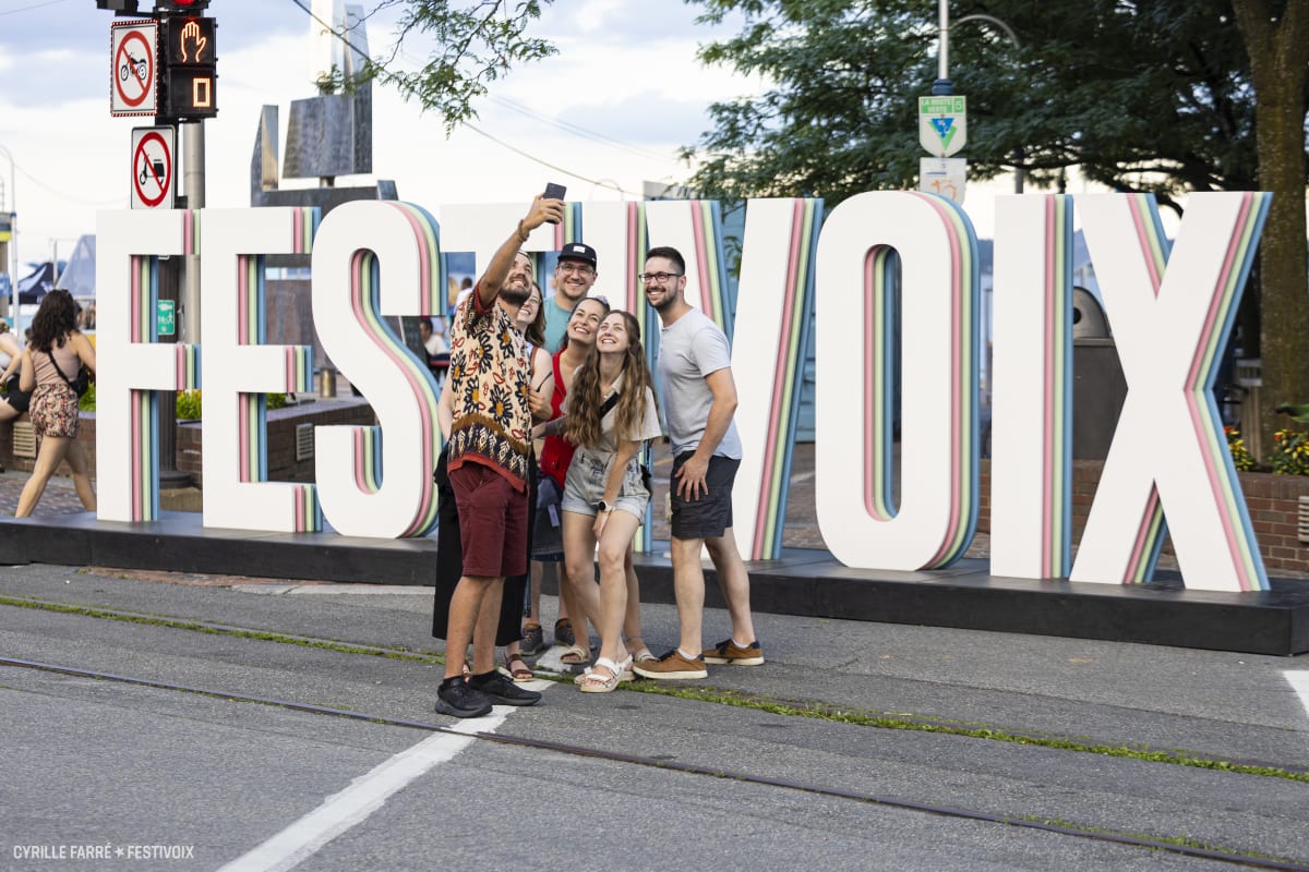Friends taking a selfie in front of FestiVoix de Trois-Rivières.