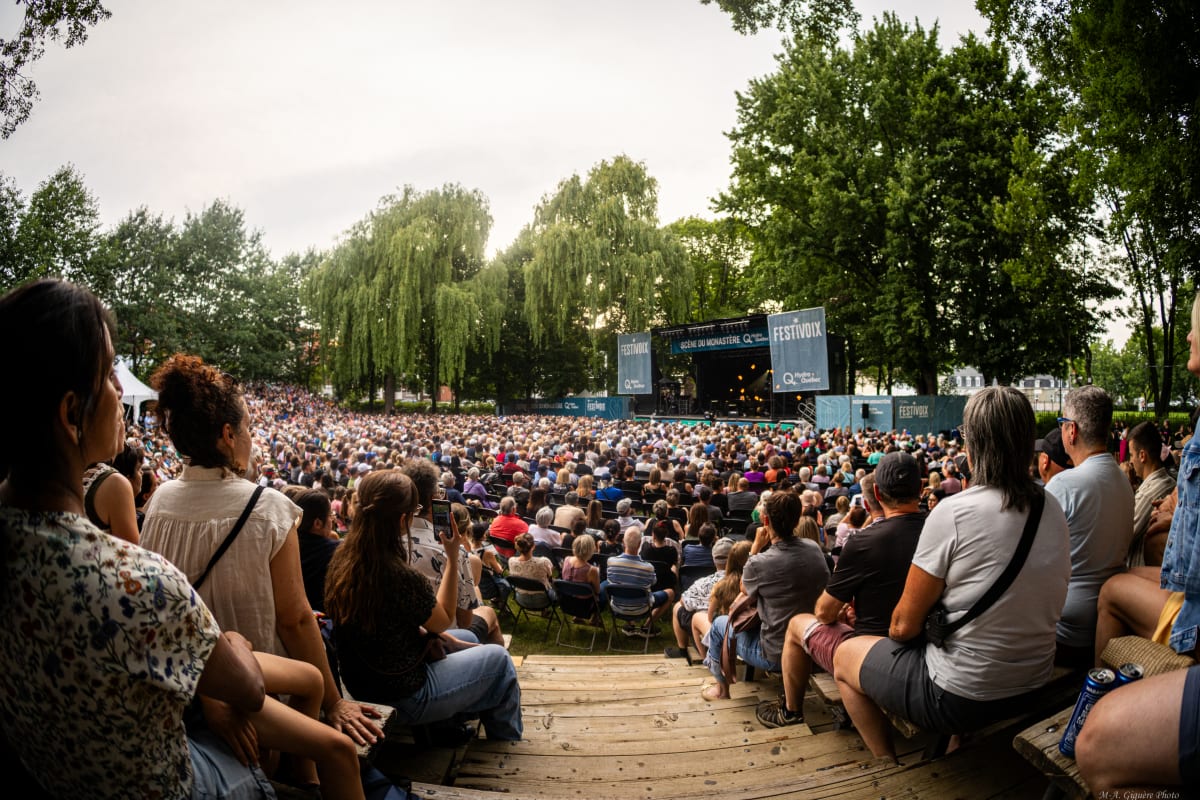 A seated crowd watches an outdoor stage at the FestiVoix de Trois-Rivières.