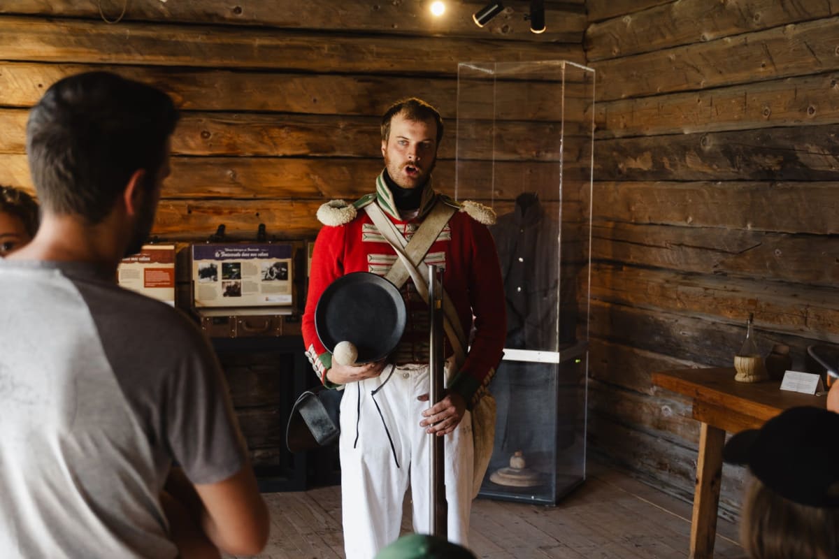 A soldier in uniform standing in front of a family in an old wooden building.