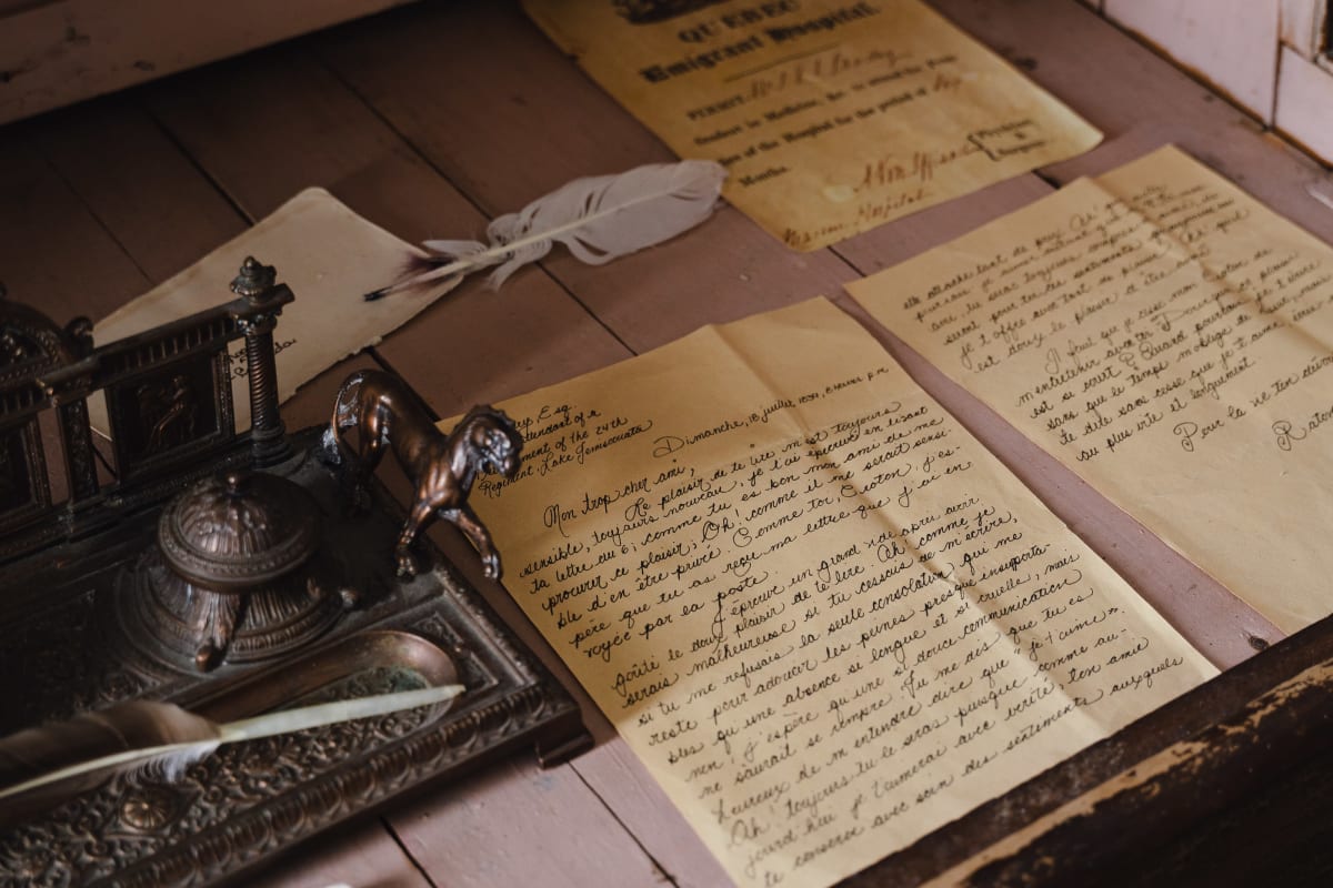 Writing quills with yellowed handwritten pages.