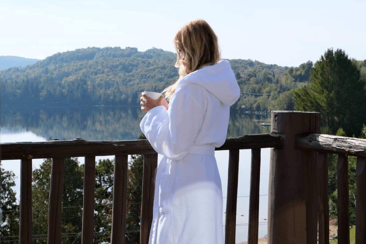 A young woman in a bathrobe enjoying her coffee on the balcony.