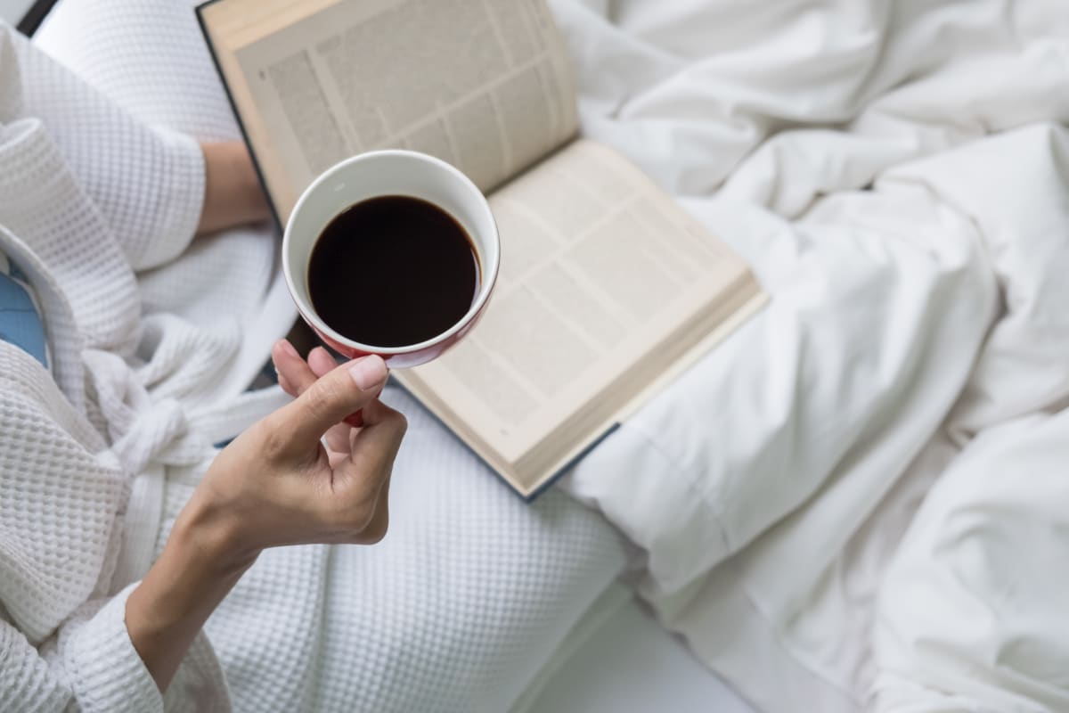 Woman lying in bed with a cup of coffee.