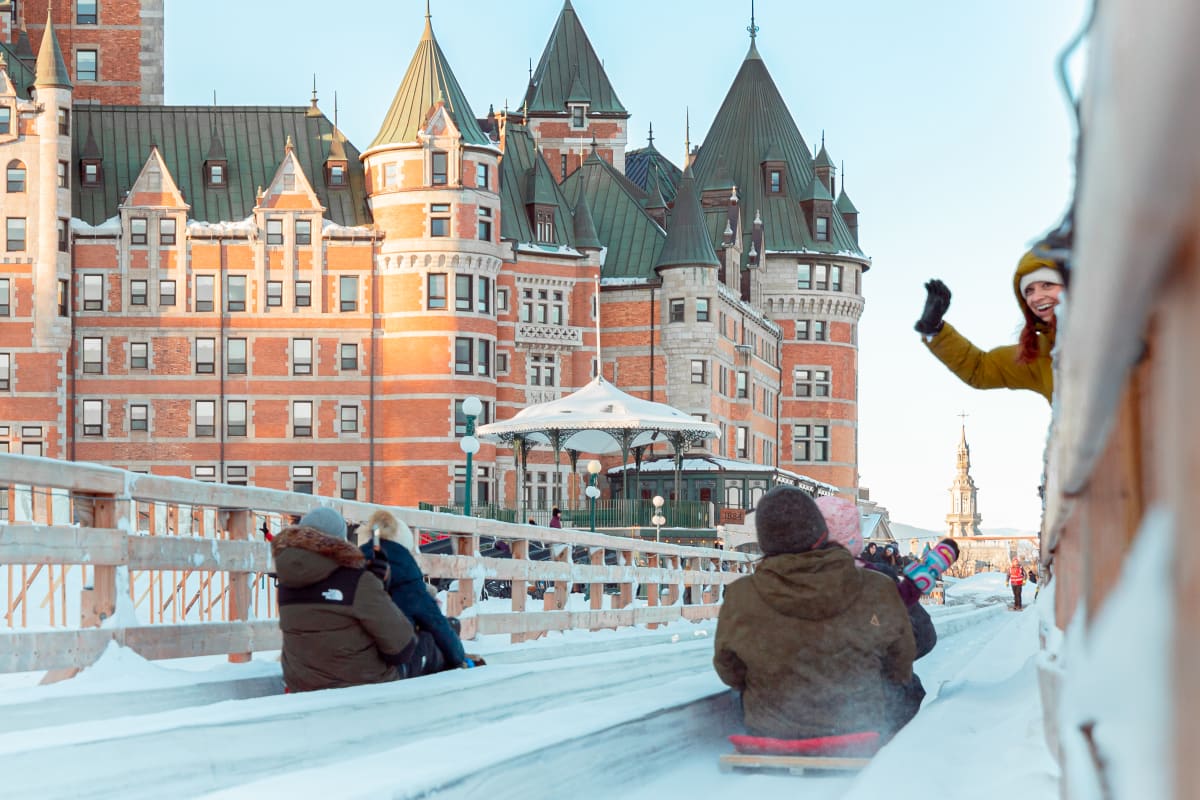 Two couples on sleds with the Château Frontenac in the background.
