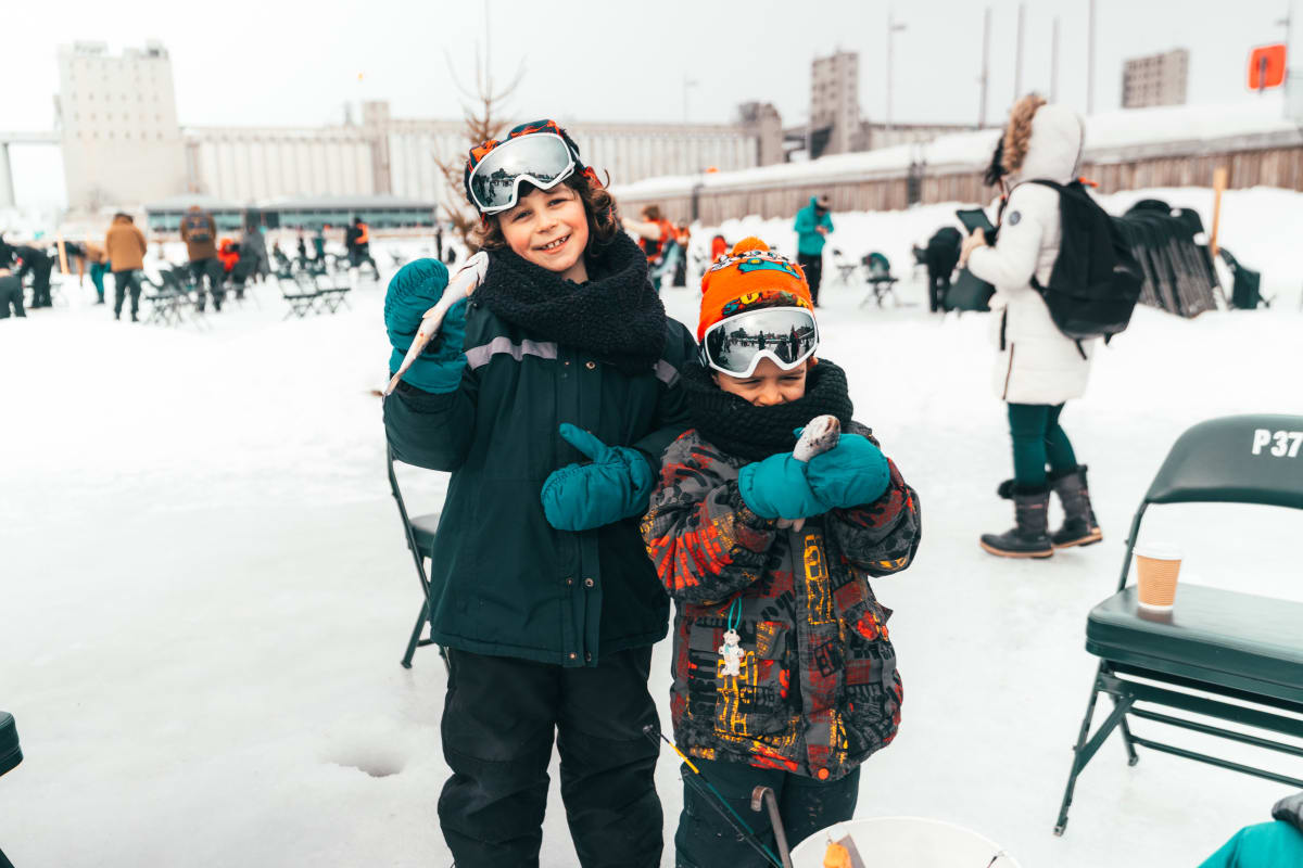 Two children ice fishing at Village Nordik.