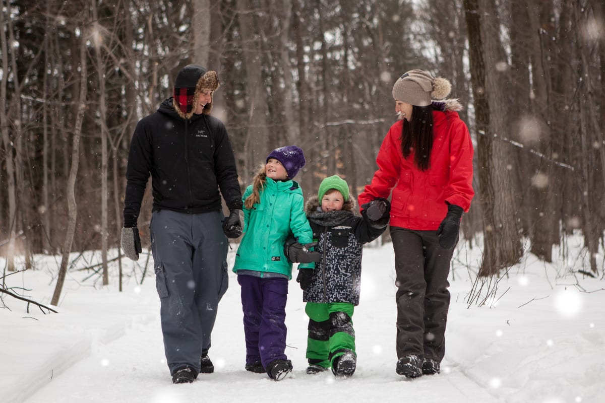 Family walking along a snow-covered forest trail.