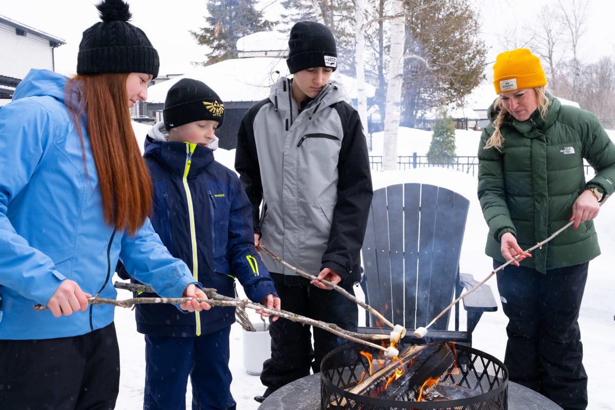 Famille faisant des guimauves grillées au feu. 
