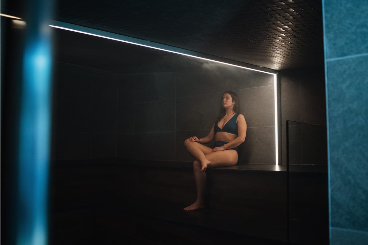 Woman relaxing in a dark sauna room.