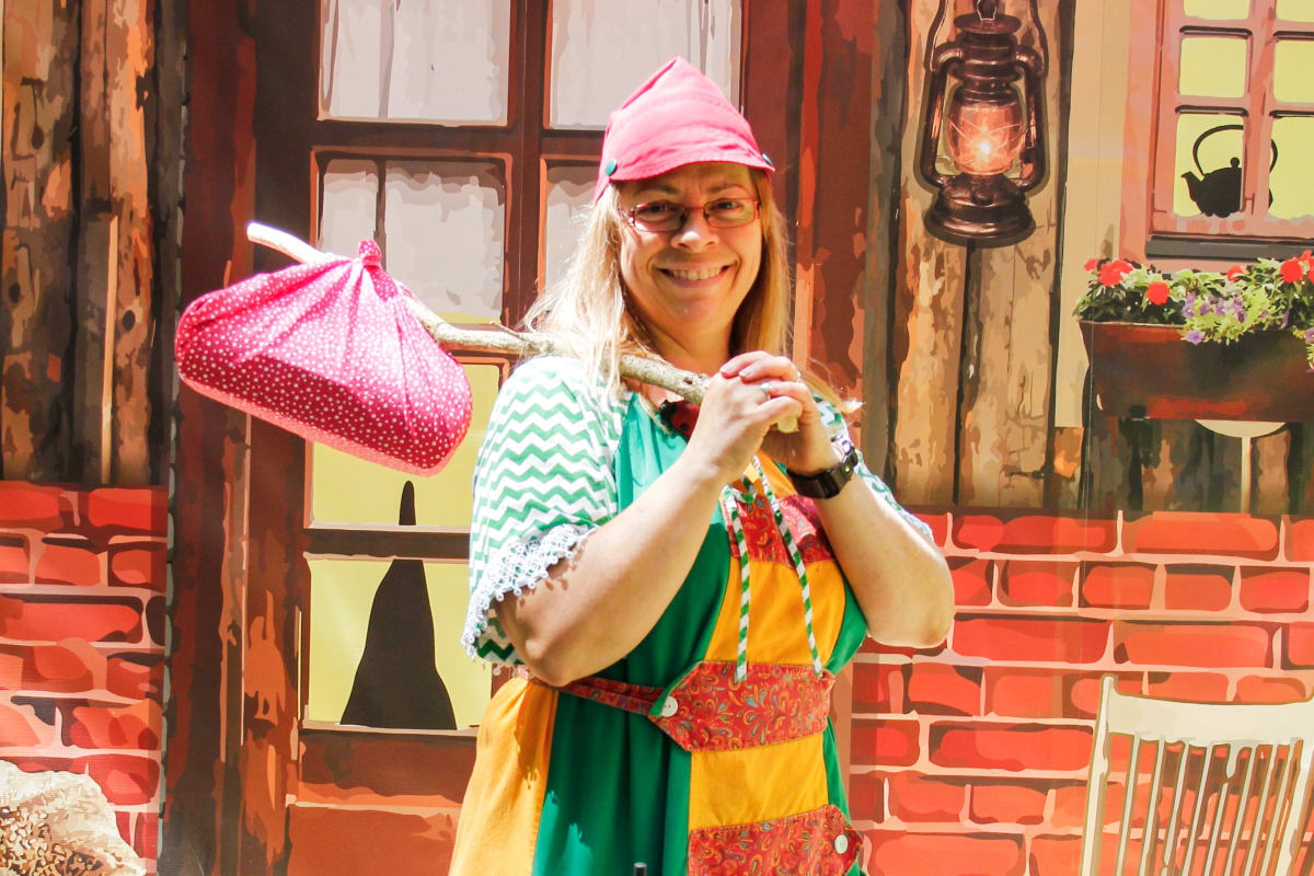 Woman carrying a bundle and wearing a fun costume at la Vallée Secrète.