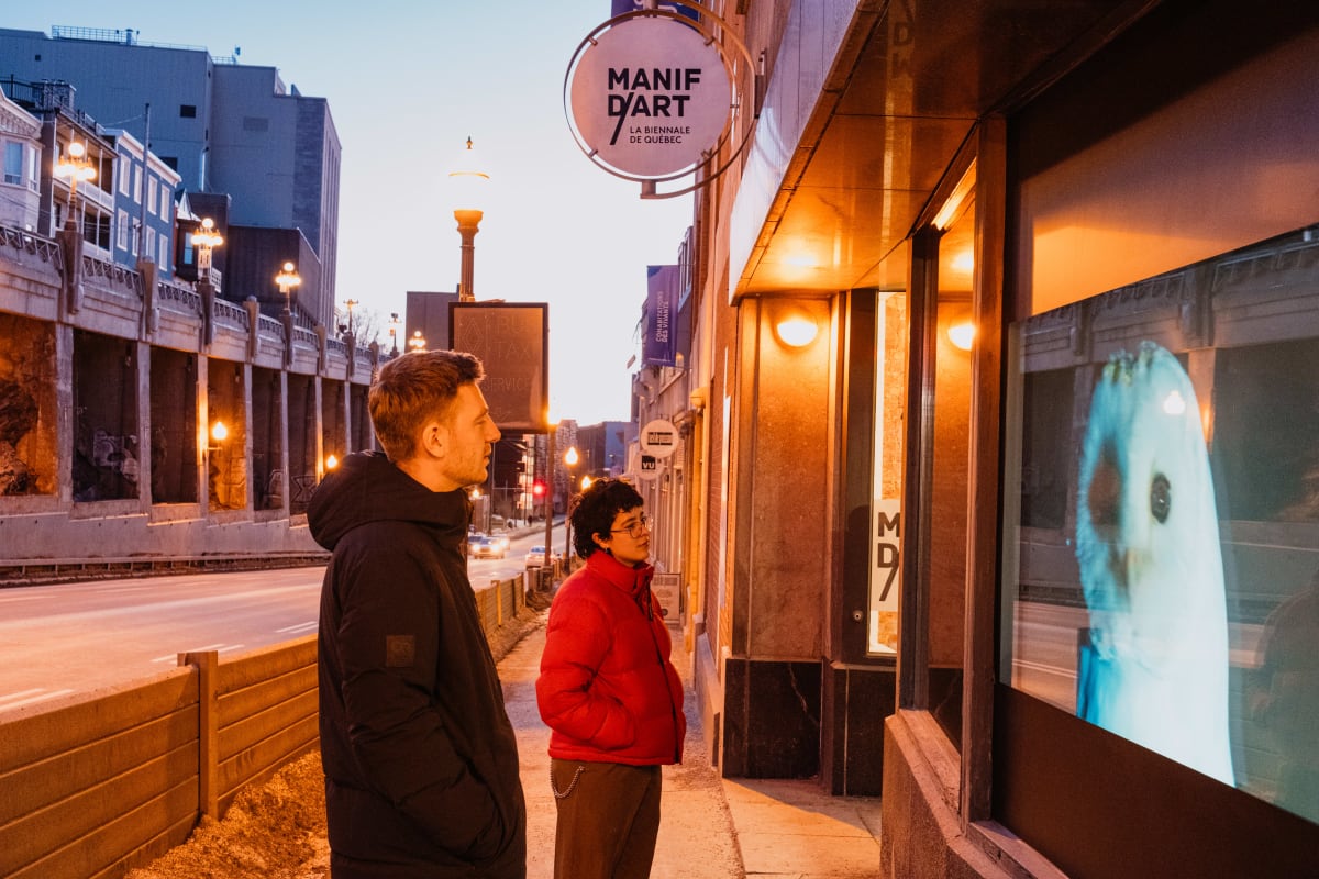 Two people looking at a work of art in front of a display window.