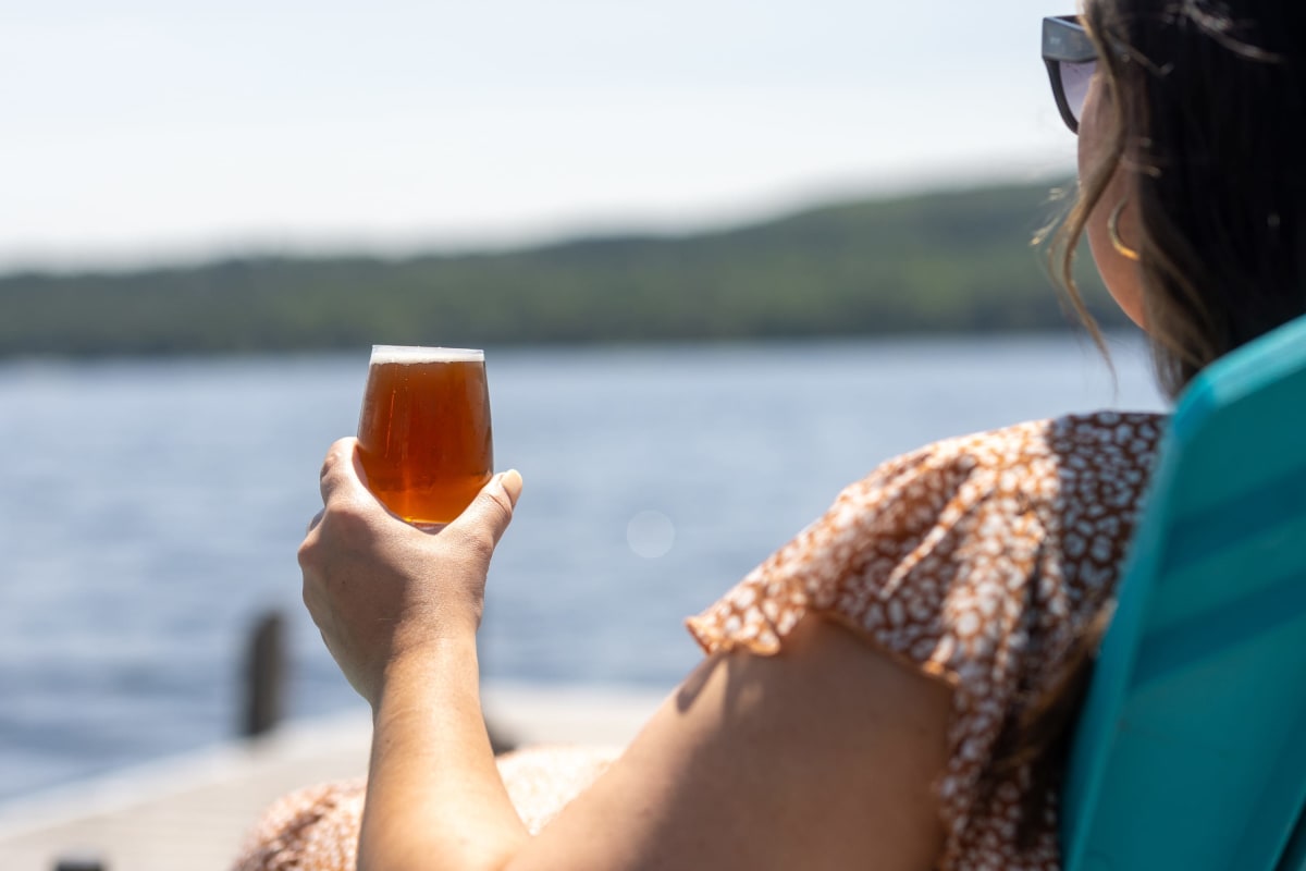 Dame avec bière sur le bord du lac