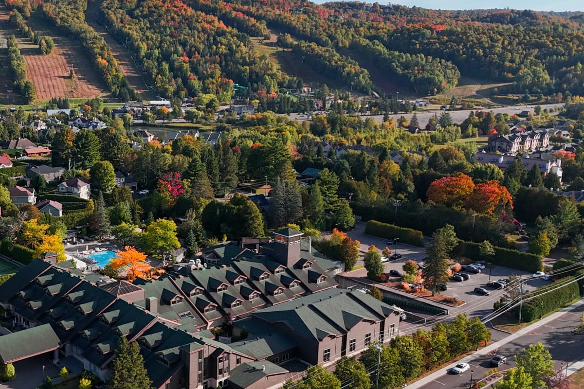 Vue aérienne de l'Hôtel-Manoir Saint-Sauveur en début d'automne, avec le mont Saint-Sauveur en arrière-plan.