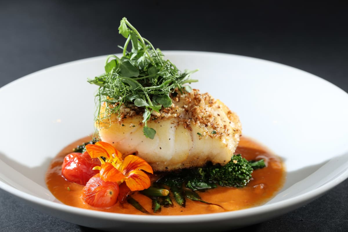 Gros plan d'une assiette soigneusement présentée de poisson en sauce.