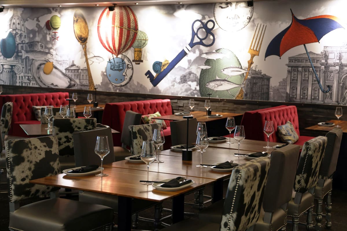 Tables à l'intérieur du restaurant Le M Steak Moderne; le décor est accentué d'éléments rouges.