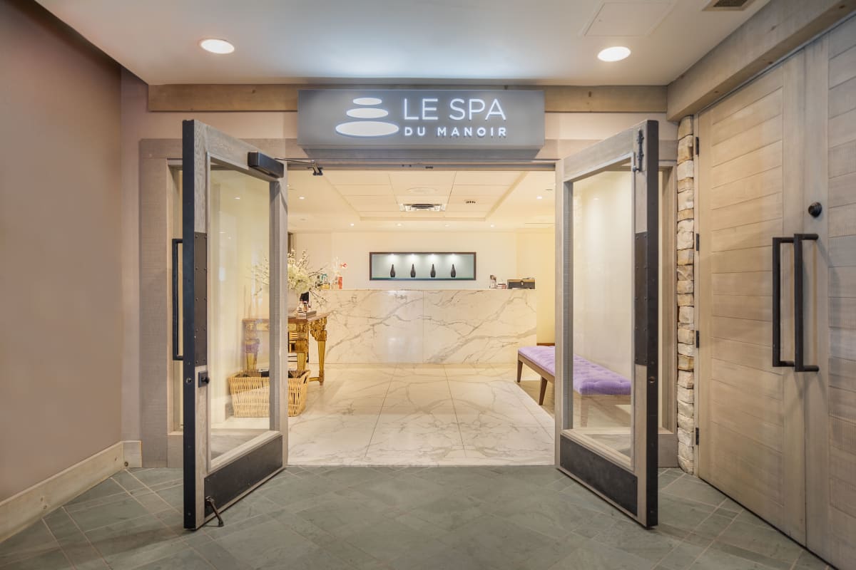 Entrée du Spa du Manoir, avec deux portes vitrées grandes ouvertes sur une pièce lumineuse. 