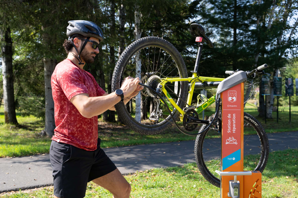 Cyclist fixing his bike on the P'tit train du Nord linear park