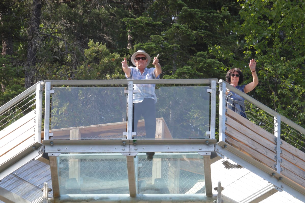 Two visitors on the glass floor at Parc le Trou de la Fée