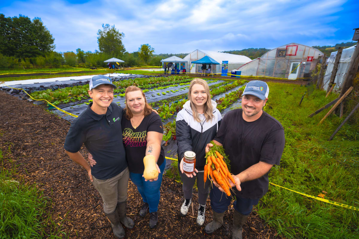 Deux couples dans un champ avec des carottes et produits de la ferme.