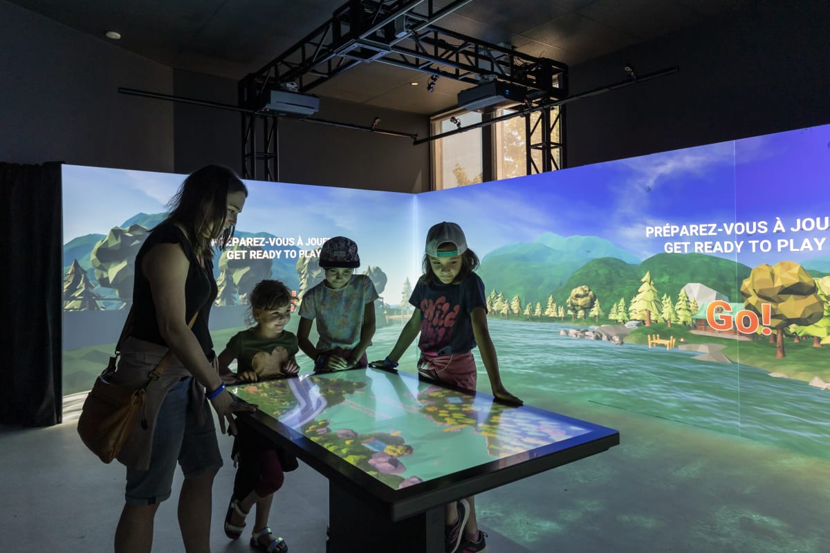 4 kids around an interactive display at the Acoatica exhibit.