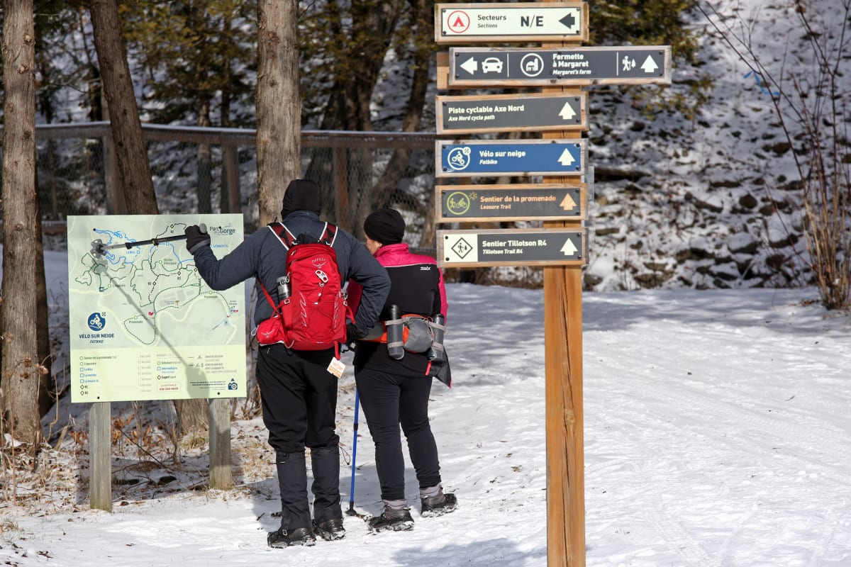 A man and a woman hiking in the winter at the Coaticook Gorge Park.