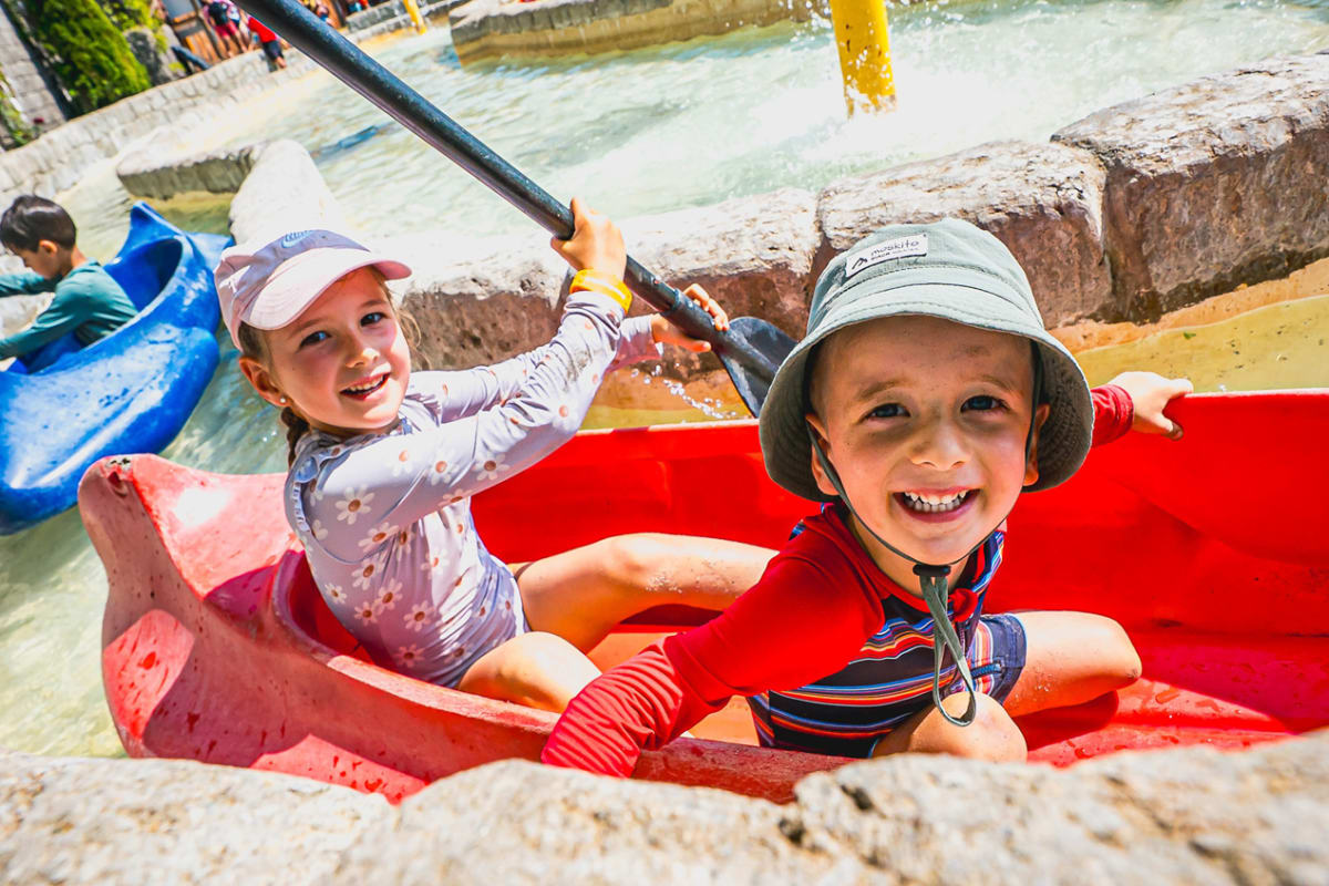 Two young children in a small kayak on a calm water circuit at the Super Aqua Club
