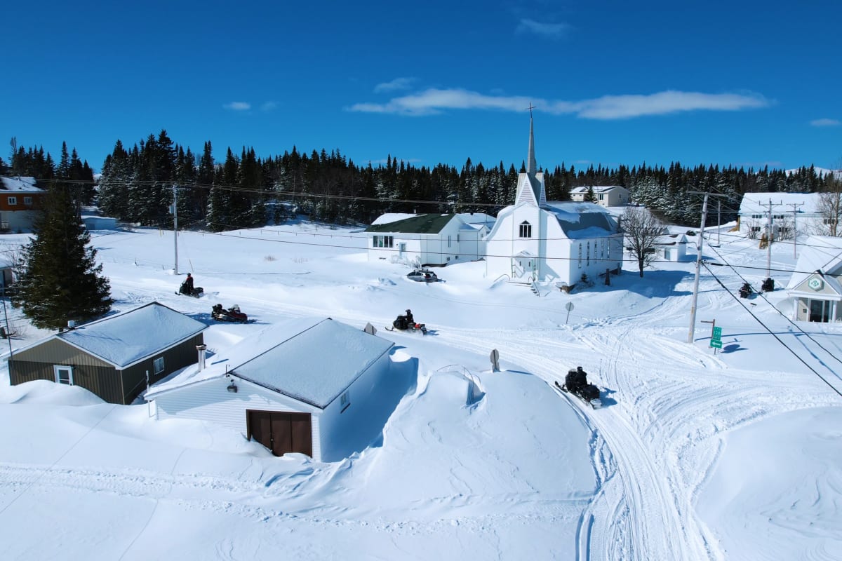 Groupe en motoneige dans un village enneigé.