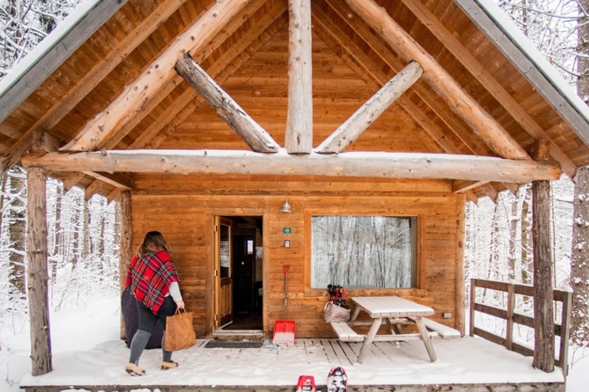 Front of a wooden cabin in winter at Huttopia - Les Deux Lacs