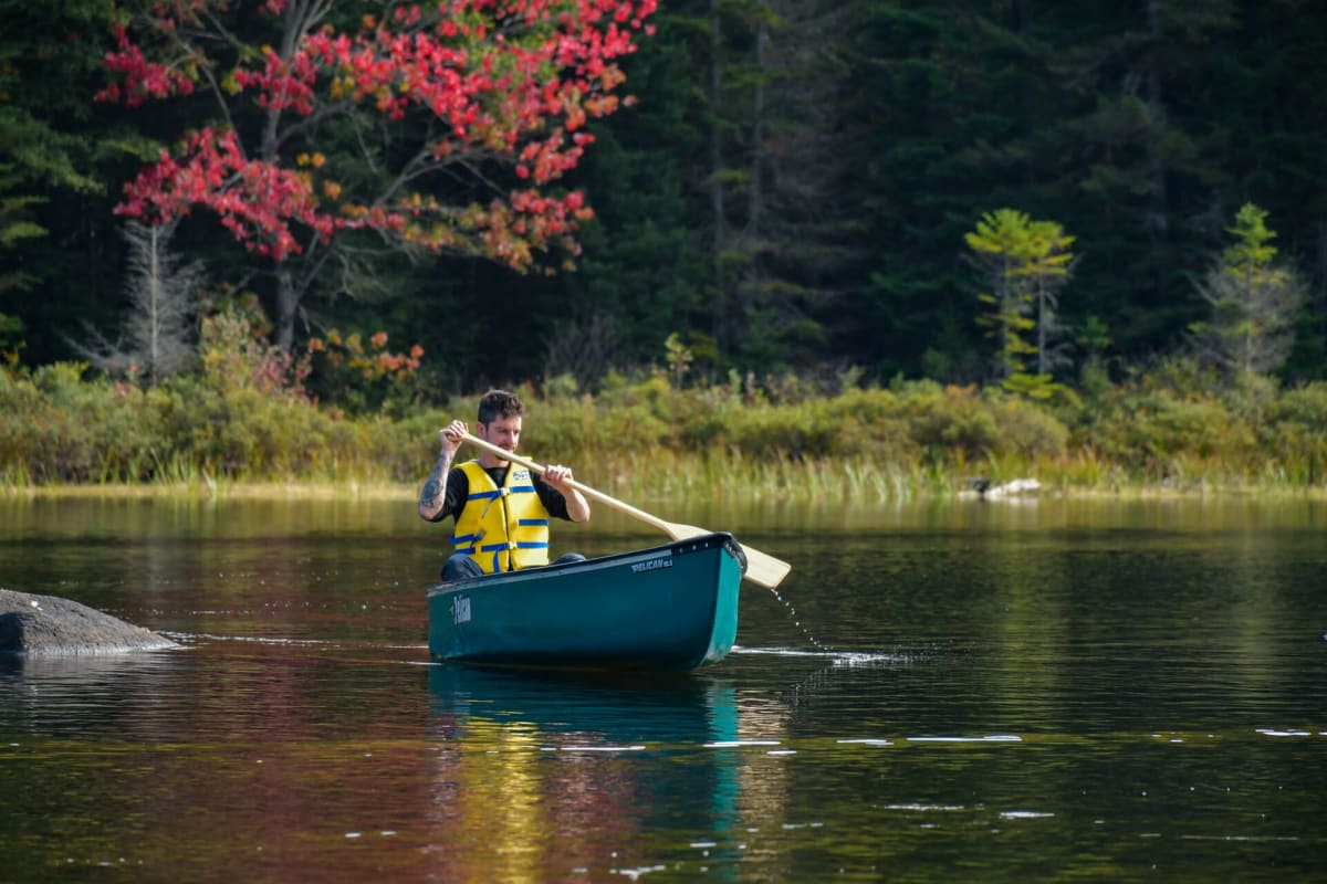 Homme en canot sur un lac à l'automne.
