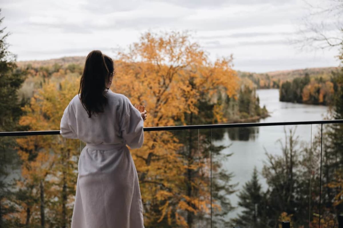 Femme en peignoir regardant un lac et paysage d'automne, Domaine des Constellations.