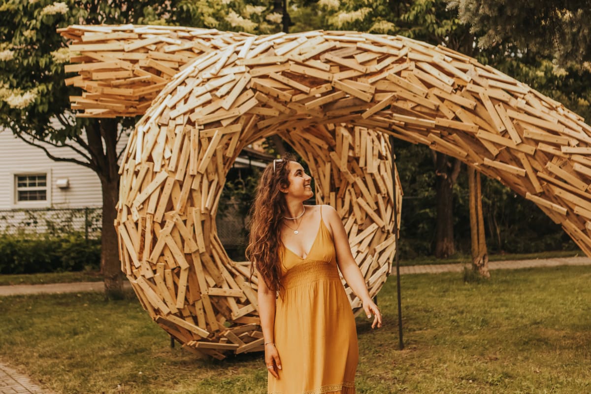 Femme devant une sculpture dans un parc. 