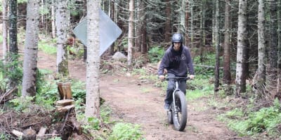 Centre récréotouristique des Hautes Terres - An individual riding a fatbike in a forest