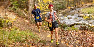 Défi des Couleurs Simard - Deux individus en train de courir dans une forêt automnale