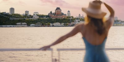 A woman is on the ferry, admiring the view of Château Frontenac