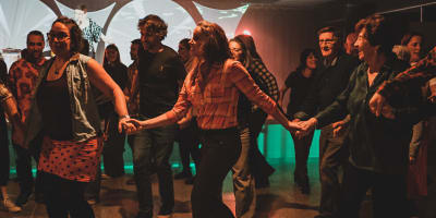 Festival de musique Trad Val-d'Or - Des gens dansent en ligne en se tenant les mains.