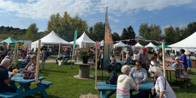 Festival des artisans de Sainte-Marcelline-de-Kildare - Un espace avec des tables de pique-nique et des chapiteaux blancs