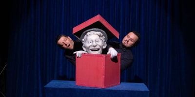 Festival international des arts de la marionnette - A puppet is in a red box. Two men stand next to it.