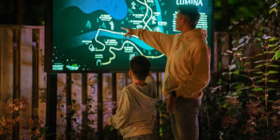 Foresta Lumina au Parc de la Gorge de Coaticook - A man and a boy point to an illuminated map.