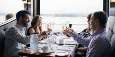 Hôtel Verso - Four adults sitting around a table in a restaurant with a view of the water.