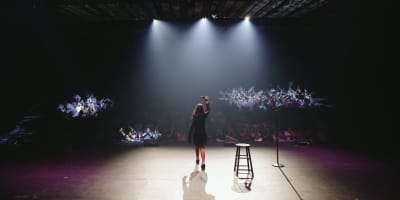 Just For Laughs MONTRÉAL - On a stage, a comedian is illuminated by spotlights.
