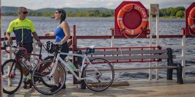 Une homme et une femme sont debout sur le bord de l'eau, avec leur vélo à leur côté