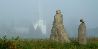 Les Amis du Patrimoine de Saint-Venant-de-Paquette - Deux sculptures en pierre, avec une église en arrière-plan