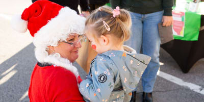 Marché de Noël de Prévost - Une femme déguisée en Mère Noël tient un enfant dans ses bras.