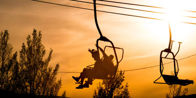 Parc vélo Sommet Saint-Sauveur - Deux personnes assises dans un remonte-pente au coucher du soleil