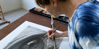 Tour des Arts - Une artiste travaille sur un dessin au fusain très détaillé d'un œil humain