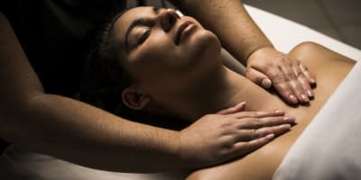 A woman lying on her back getting a shoulder massage.