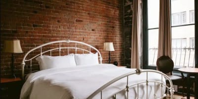 Bed in a room with an exposed brick wall at Auberge du Vieux-Montréal