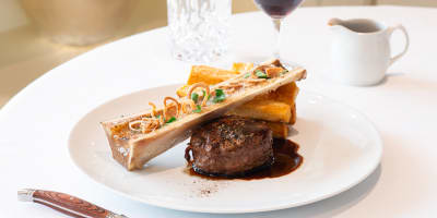 Gourmet plate featuring beef tenderloin, bone marrow, and brown sauce.