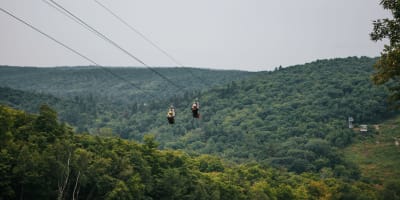 Deux personnes en tyrolienne en été.