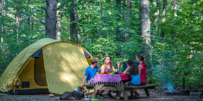 Famille assise à une table de pique-nique au Camping du parc national d'Oka.